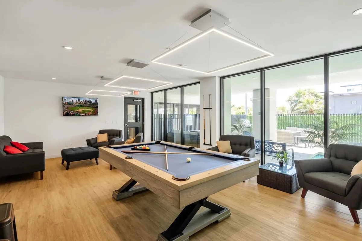 An inviting clubhouse interior featuring a pool table, seating area, TV, and large windows. The space is designed for friendly competitions, group hangouts, or unwinding after a night out. The relaxed yet social layout encourages communal experiences and leisure, mirroring the post-nightlife activities mentioned in the section.