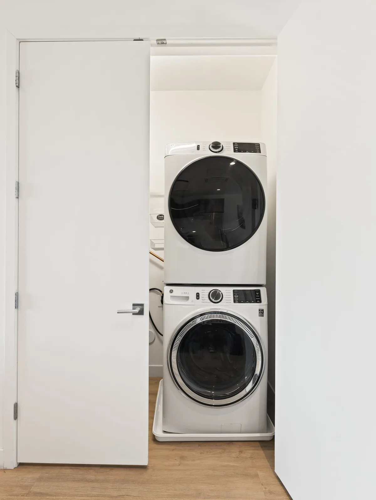 A compact laundry area featuring a washer and dryer set beneath white cabinetry, creating a practical and efficient environment.